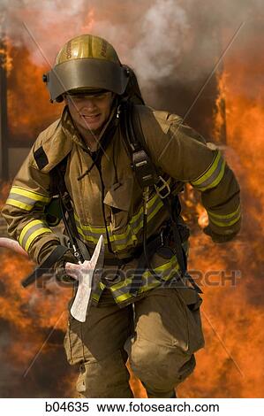 Stock Photography - Firefighter with axe running from blaze. Fotosearch