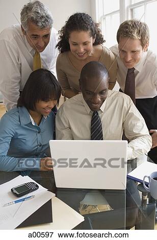 Five businesspeople looking at laptop smiling View Large Photo Image Stock Photo - Five businesspeople looking at laptop smiling. Fotosearch