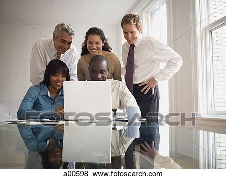 Stock Photo - Five businesspeople looking at laptop smiling. Fotosearch