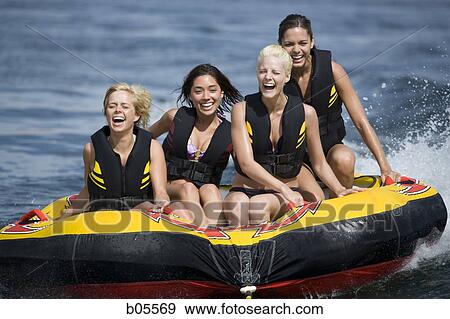 Four women on inner tube wearing life jackets View Large Photo Image Stock Photo - Four women on inner tube wearing life jackets. Fotosearch