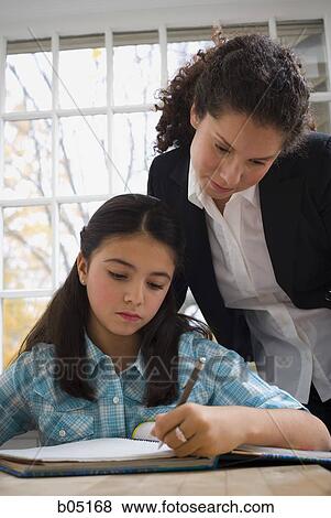 Girl doing homework with woman watching View Large Photo Image Stock Photo - Girl doing homework with woman watching. Fotosearch
