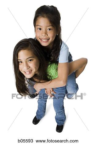 Stock Image - Girl giving piggy back ride to younger girl. Fotosearch