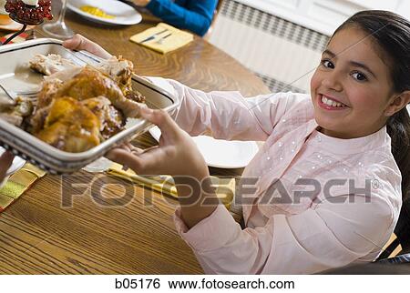 Girl holding food at dinner table View Large Photo Image Stock Photograph - Girl holding food at dinner table. Fotosearch