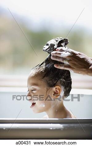 Stock Image - Girl in bathtub having hair washed. Fotosearch