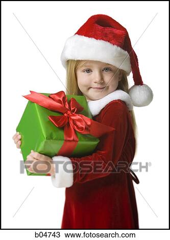 Stock Image - Girl in santa hat holding Christmas present. Fotosearch