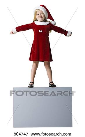 Stock Photo - Girl in santa hat with arms up standing on blank sign. Fotosearch
