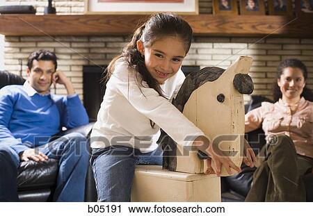 Girl on hobby horse with man and woman smiling View Large Photo Image Stock Image - Girl on hobby horse with man and woman smiling. Fotosearch