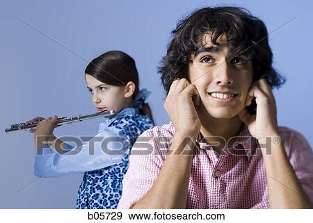 Girl playing the flute with her brother not listening View Large Photo Image Stock Photo - Girl playing the flute with her brother not listening. Fotosearch