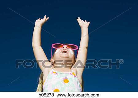 Stock Photo - Girl with suntan lotion and sunglasses smiling with arms up. Fotosearch