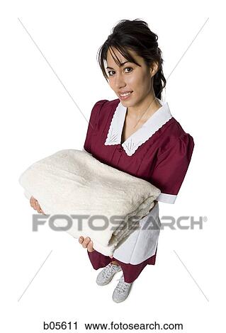 Stock Image - Maid standing with towels. Fotosearch