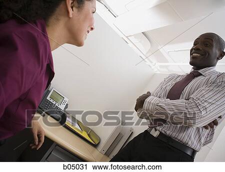 Stock Image - Make and female colleagues talking. Fotosearch