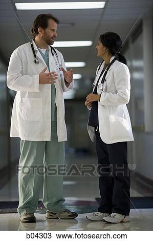 Male and female doctor talking in corridor View Large Photo Image Stock Image - Male and female doctor talking in corridor. Fotosearch