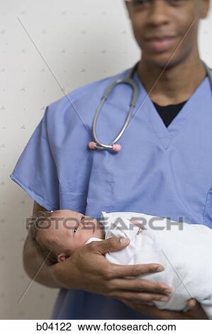 Male Doctor holding newborn baby View Large Photo Image Stock Image - Male Doctor holding newborn baby. Fotosearch
