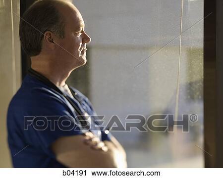 Male doctor looking through window View Large Photo Image Stock Image - Male doctor looking through window. Fotosearch