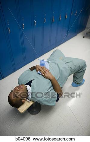 Stock Photograph - Male doctor resting on bench in scrubs. Fotosearch