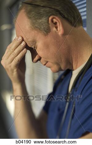 Male doctor rubbing forehead View Large Photo Image Stock Image - Male doctor rubbing forehead. Fotosearch