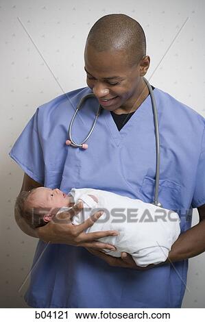Male Doctor smiling at newborn baby View Large Photo Image Stock Image - Male Doctor smiling at newborn baby. Fotosearch