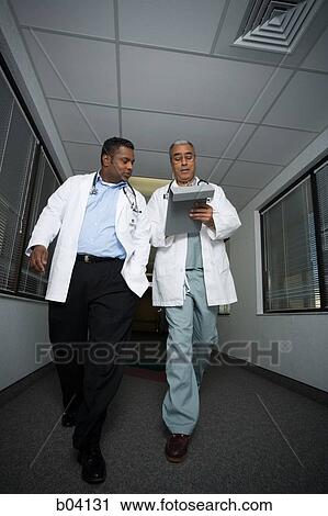 Male doctors walking and talking View Large Photo Image Stock Image - Male doctors walking and talking. Fotosearch