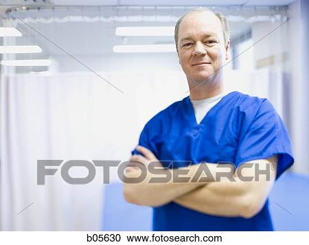 Stock Image - Male health care worker standing with crossed arms smiling. Fotosearch