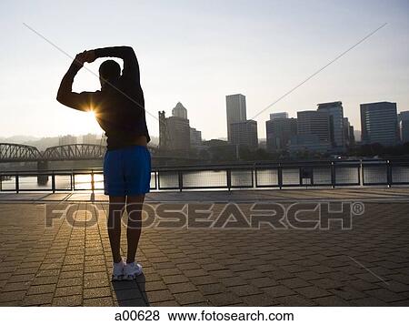 Male jogger stretching at sunrise View Large Photo Image Stock Photo - Male jogger stretching at sunrise. Fotosearch