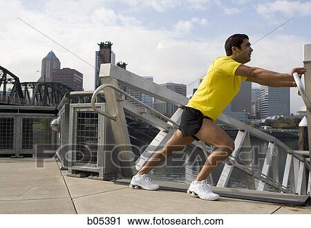 Stock Image - Male jogger stretching outdoors in city. Fotosearch