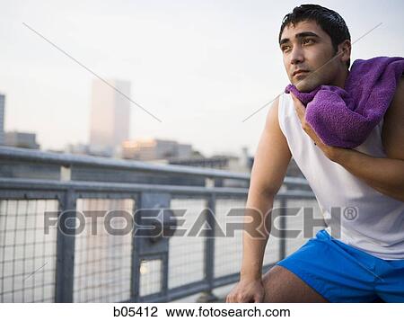 Stock Image - Male jogger with towel drying off outdoors. Fotosearch