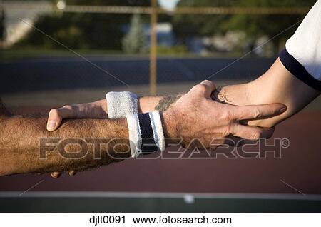 Stock Image - Male Tennis Players shaking hands on the court. Fotosearch