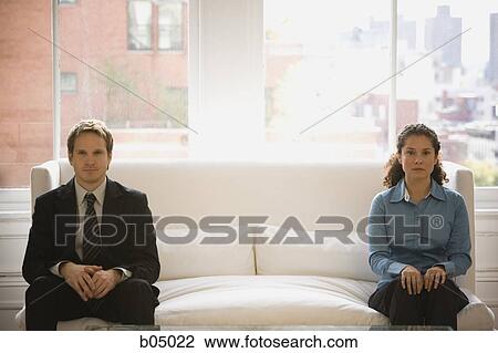 Stock Image - Man and woman at each end of sofa. Fotosearch