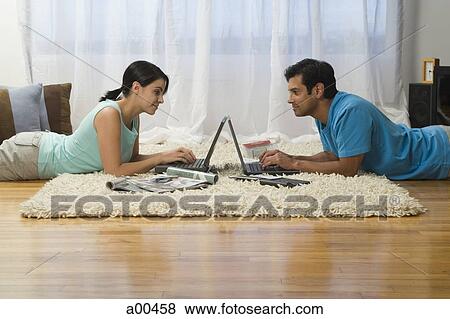 Man and woman lying on carpet with laptops View Large Photo Image Stock Photo - Man and woman lying on carpet with laptops. Fotosearch