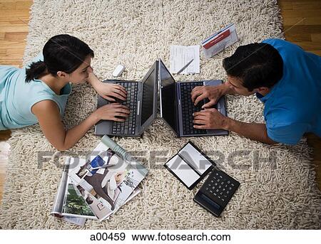 Man and woman lying on carpet with laptops View Large Photo Image Stock Photo - Man and woman lying on carpet with laptops. Fotosearch