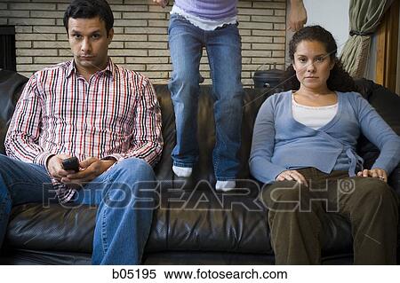 Man and woman on sofa with girl jumping View Large Photo Image Stock Photography - Man and woman on sofa with girl jumping. Fotosearch