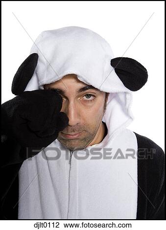 Stock Image - Man dressed in panda costume rubbing his eye. Fotosearch