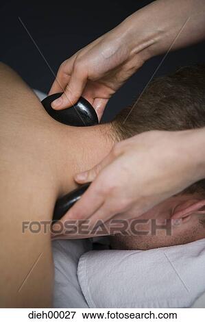 Stock Photo - Man having a neck massage with rocks. Fotosearch