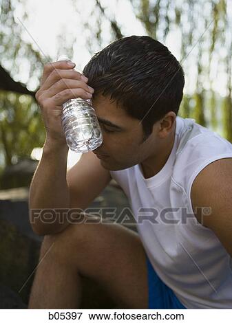 Man holding bottled water to forehead View Large Photo Image Stock Photo - Man holding bottled water to forehead. Fotosearch
