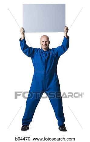 Man on overalls standing with blank sign View Large Photo Image Stock Image - Man on overalls standing with blank sign. Fotosearch