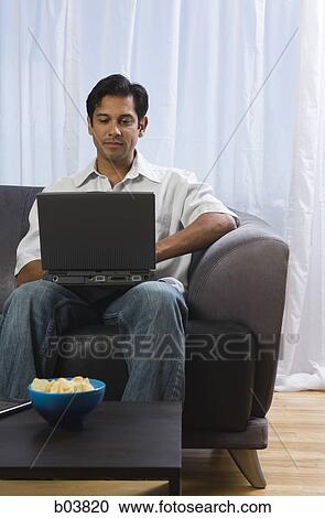 Man on sofa with laptop and bowl of potato chips View Large Photo Image Stock Image - Man on sofa with laptop and bowl of potato chips. Fotosearch