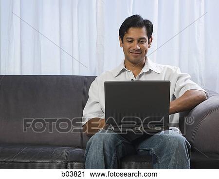 Man on sofa with laptop smiling View Large Photo Image Stock Image - Man on sofa with laptop smiling. Fotosearch