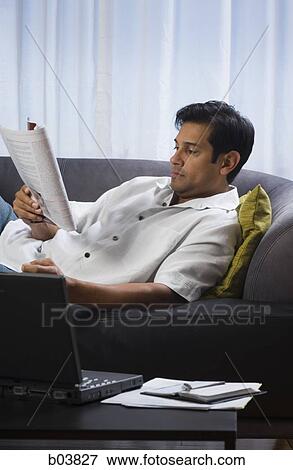 Stock Photo - Man on sofa with magazine. Fotosearch