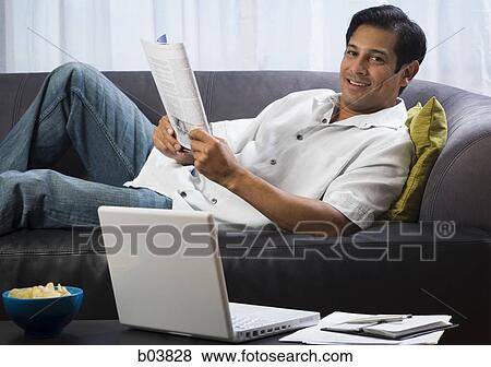 Man on sofa with magazine View Large Photo Image Stock Photo - Man on sofa with magazine. Fotosearch