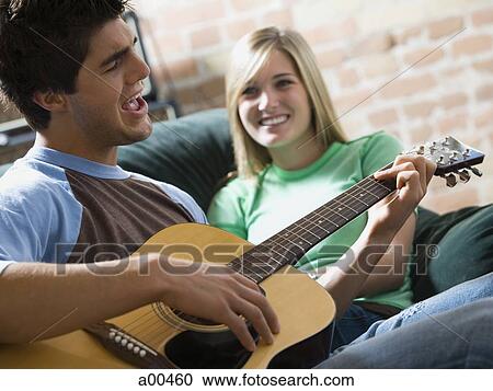 Man playing guitar and singing for woman on sofa View Large Photo Image Stock Image - Man playing guitar and singing for woman on sofa. Fotosearch