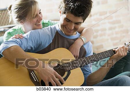 Man playing guitar with woman behind him View Large Photo Image Stock Image - Man playing guitar with woman behind him. Fotosearch