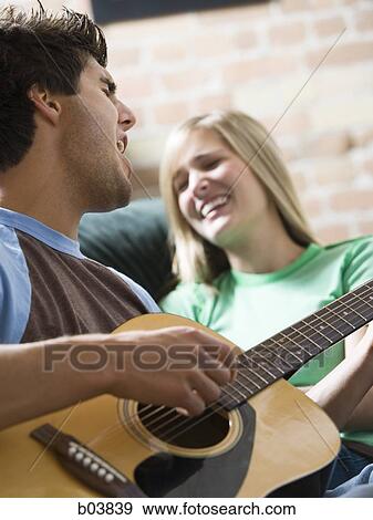 Stock Photo - Man singing with guitar for woman. Fotosearch