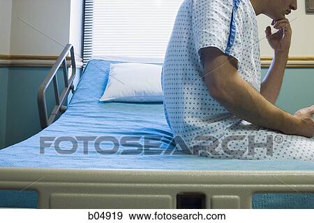 Man sitting on hospital bed in gown thinking View Large Photo Image Stock Photo - Man sitting on hospital bed in gown thinking. Fotosearch