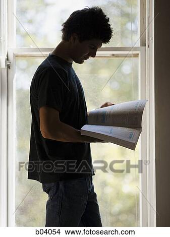 Man standing at window reading View Large Photo Image Picture - Man standing at window reading. Fotosearch