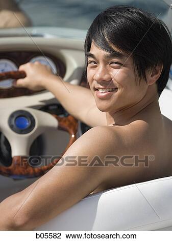 Stock Image - Man steering boat smiling. Fotosearch