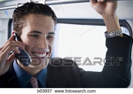 Stock Photo - Man talking on cell phone in bus or subway. Fotosearch