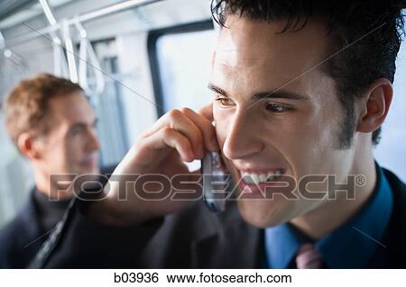Stock Photograph - Man talking on cell phone in bus or subway. Fotosearch