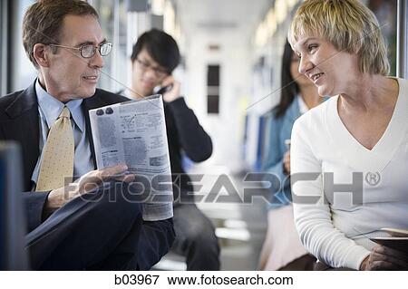 Man with newspaper talking to woman on city bus or subway View Large Photo Image Stock Photo - Man with newspaper talking to woman on city bus or subway. Fotosearch