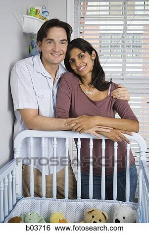 Married couple leaning on baby crib View Large Photo Image Stock Photograph - Married couple leaning on baby crib. Fotosearch