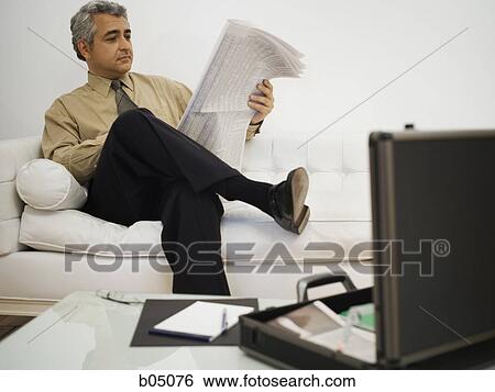 Mature businessman sitting on sofa reading newspaper View Large Photo Image Stock Photograph - Mature businessman sitting on sofa reading newspaper. Fotosearch